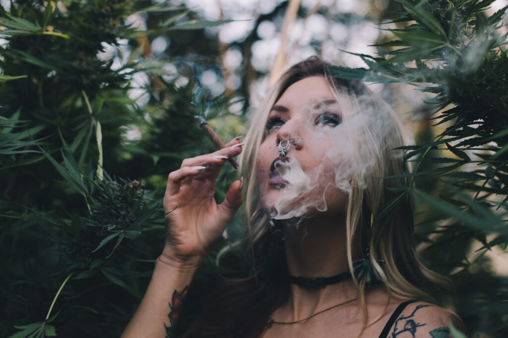 Woman smoking cannabis surrounded by plants.