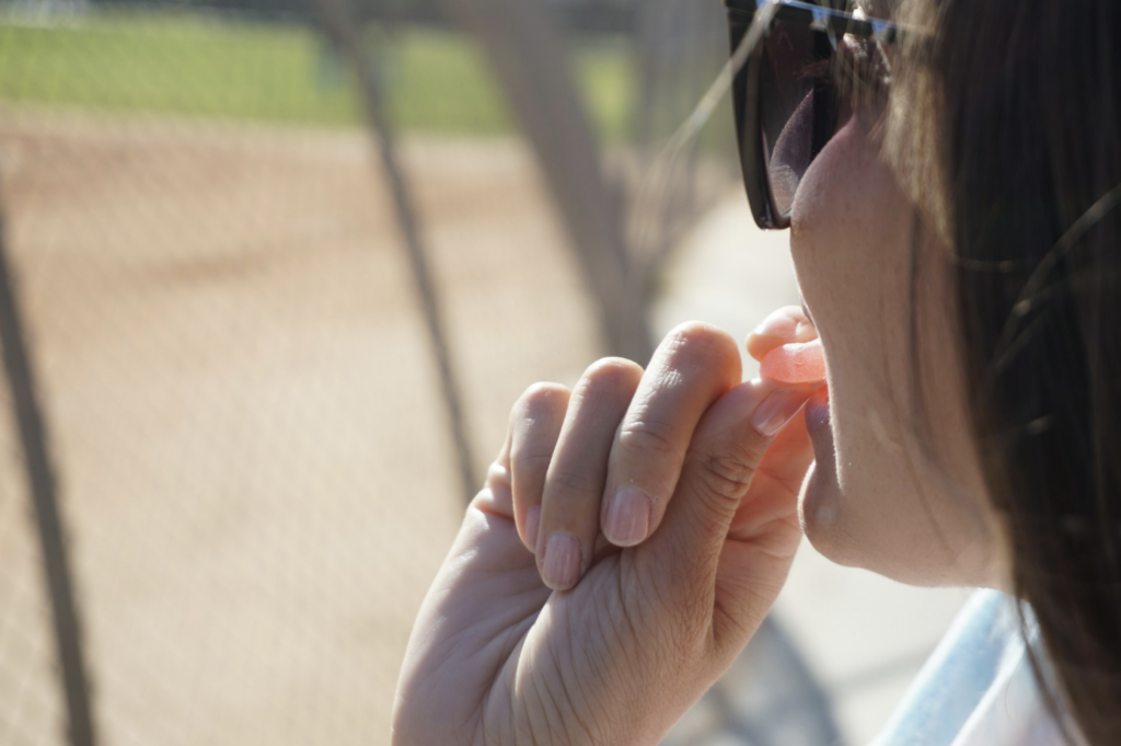 Close-up of a person eating a single THC gummy outdoors, highlighting the importance of starting with one dose and waiting at least two hours before taking more