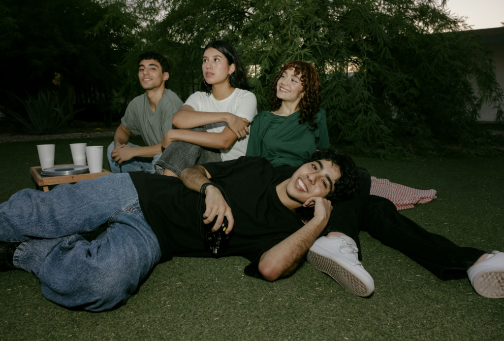 Group of friends relaxing together on the grass at dusk, illustrating the social setting where a 5 to 10 mg THC edible dose is popular among occasional cannabis users