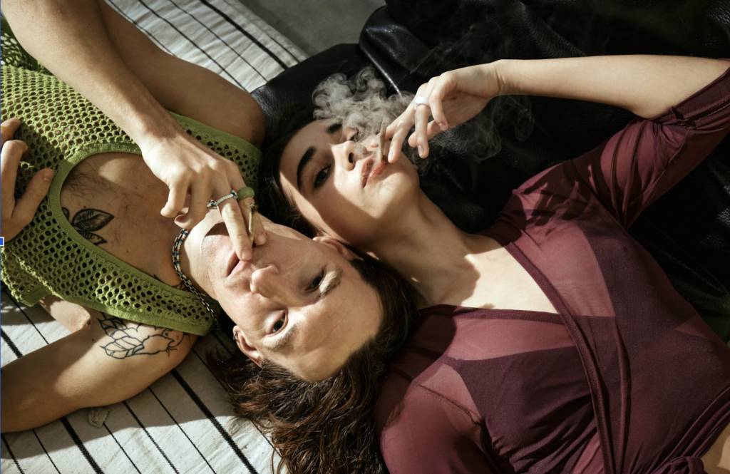 Source - Alt: Two friends lying back and sharing a cannabis joint, illustrating how the same THC dose can affect people differently due to CYP2C9 genetic variation