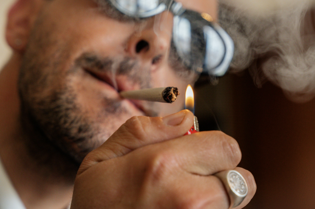 Close-up of a man lighting a cannabis joint with smoke visible, representing the legal adult-use consumption that has been permitted in New Jersey on private property since April 2022